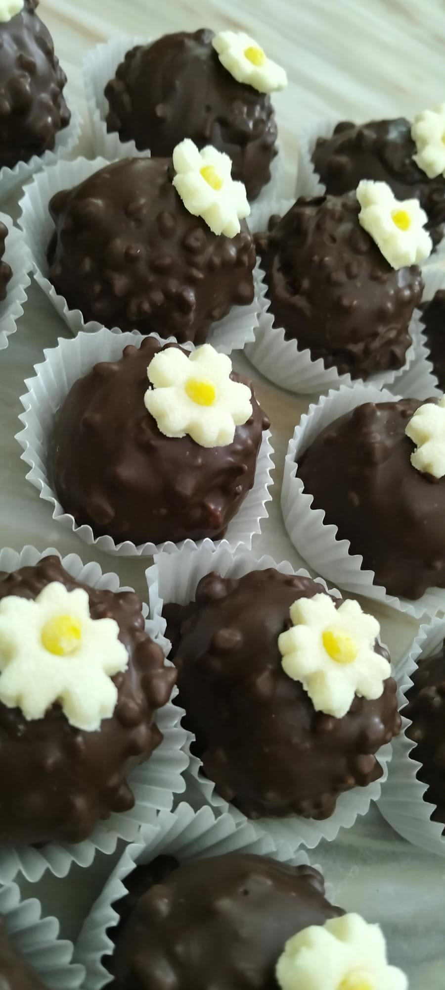 Doces de chocolate decorados com flores em creme